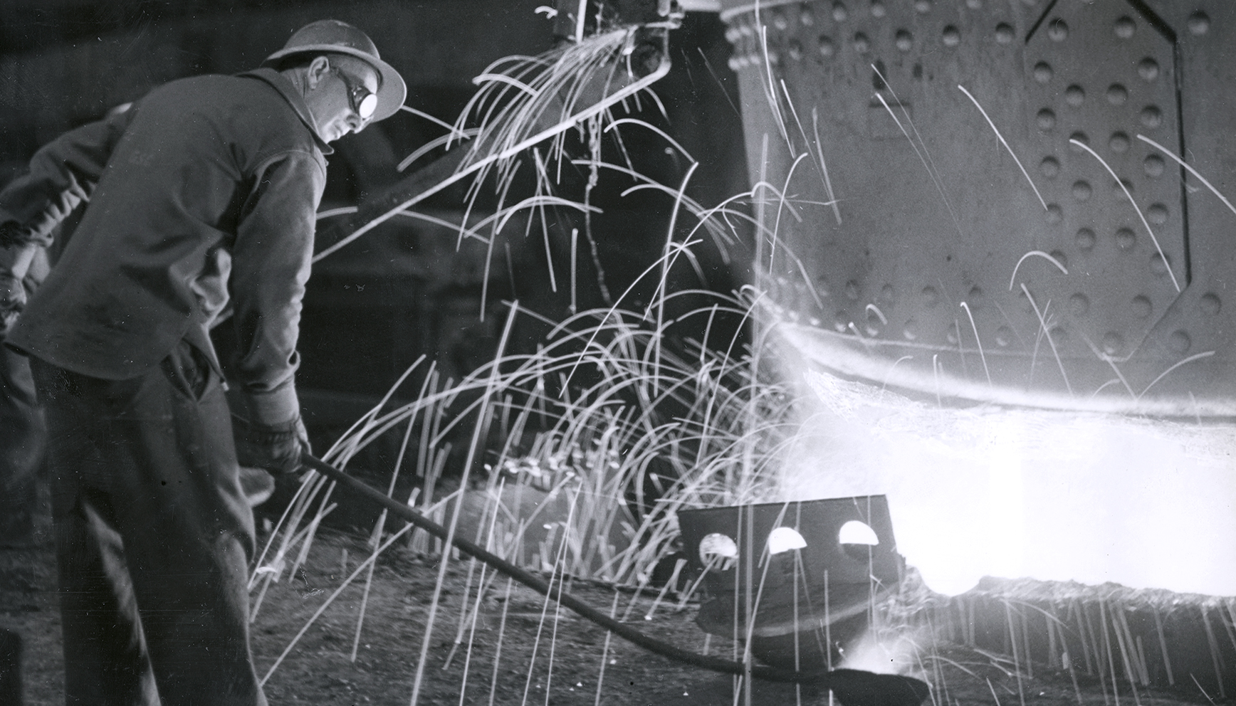 Steelworker near large machinery with sparks