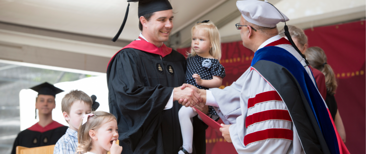 MBA student on the commencement stage with his family